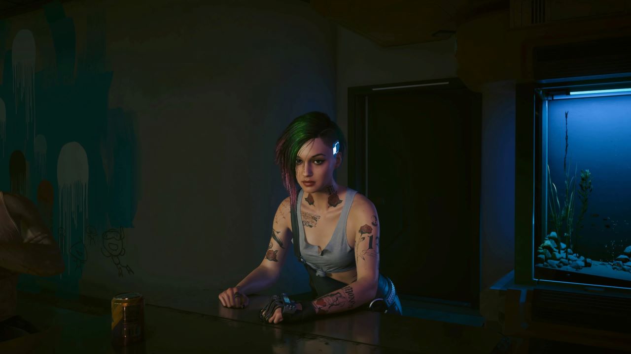 Image with the character Judy in Cyberpunk 2077 on show. She has purple to green hair and there is an aquarium in the background.