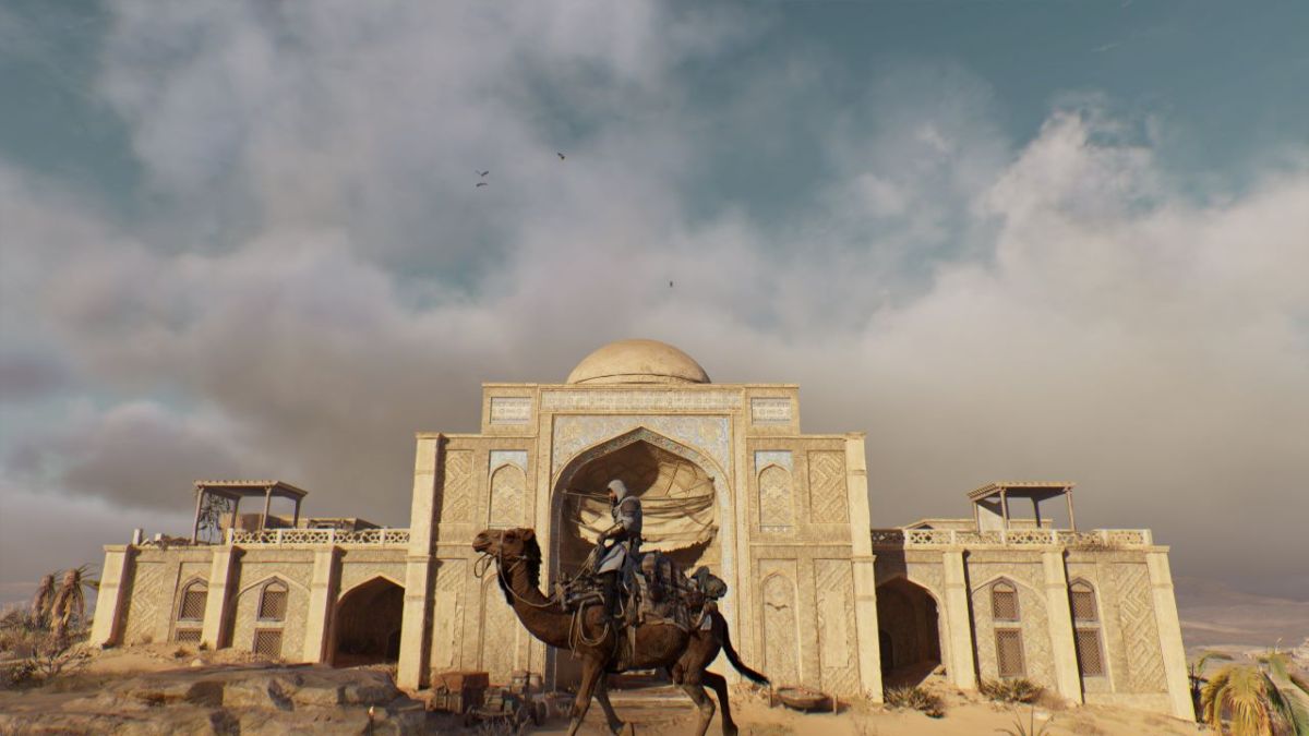 Image showcasing the Abandoned Caravanserai in Assassin's Creed Mirage. Basim is on a camel and there are birds in the skies also.