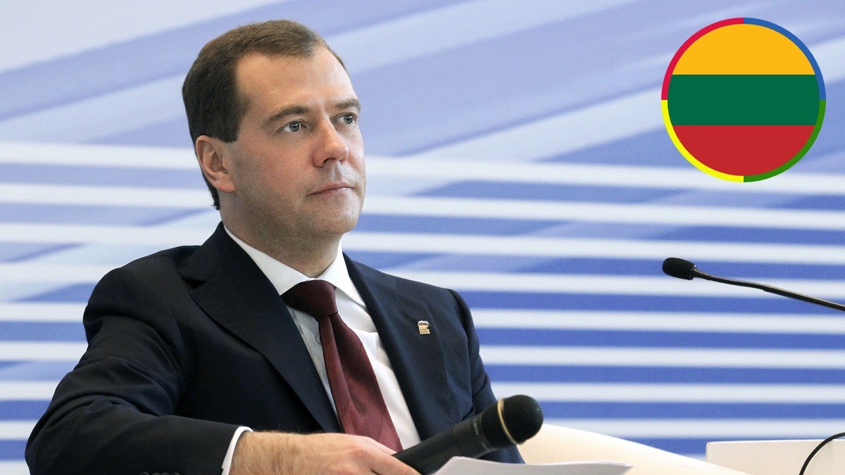 Dmitry Medvedev seated with microphones at a formal event, with an inset graphic of the Lithuanian flag in the upper-right corner.